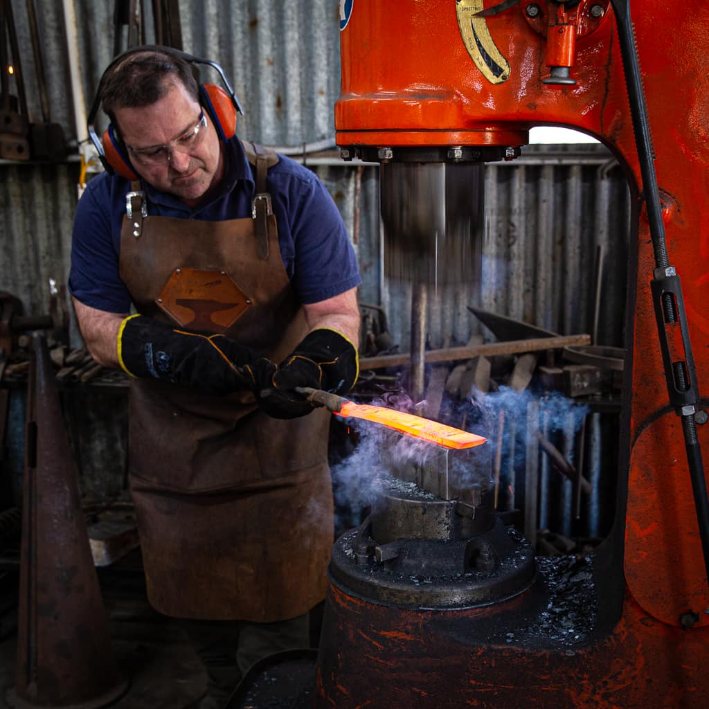 Jason Heineman using a power hammer to make Damascus steel at Tharwa Valley Forge