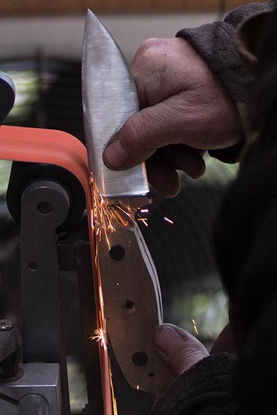 Grinding a knife on a belt grinder